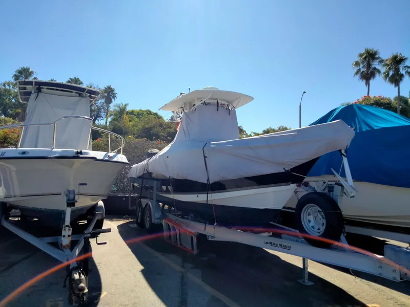 Slide: The Image of 2018 Mako 234 Center Console boat covered on a trailer, parked outdoors. - 9