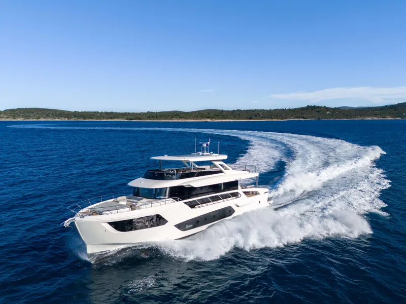 Slide: The Image of 2024 Absolute NAVETTA 75 yacht cruising on open sea with scenic coastline. - 2