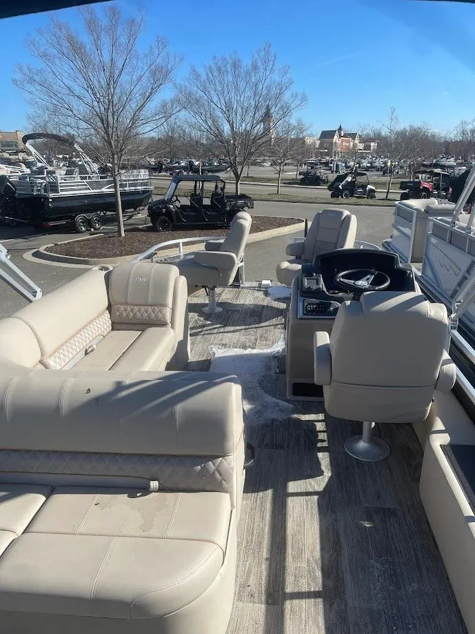 Slide: The Image of 2024 Ranger Reata 220F pontoon boat interior with beige seating and steering console. - 2