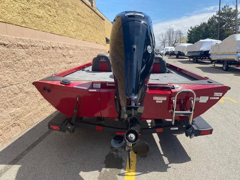 Slide: The Image of 2024 Ranger RT188 boat, red exterior, parked outdoors, rear view with motor and ladder. - 3