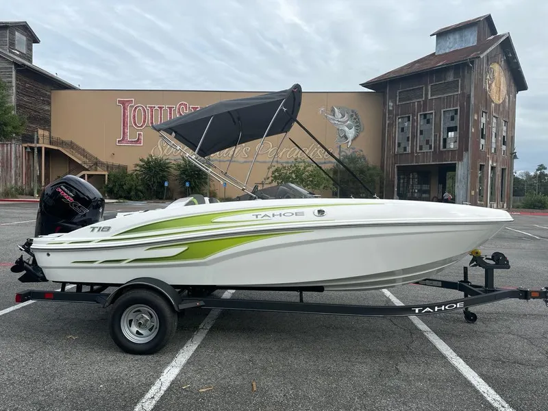 Slide: The Image of 2024 Tahoe T18 boat with green accents on a trailer in a parking lot. - 2