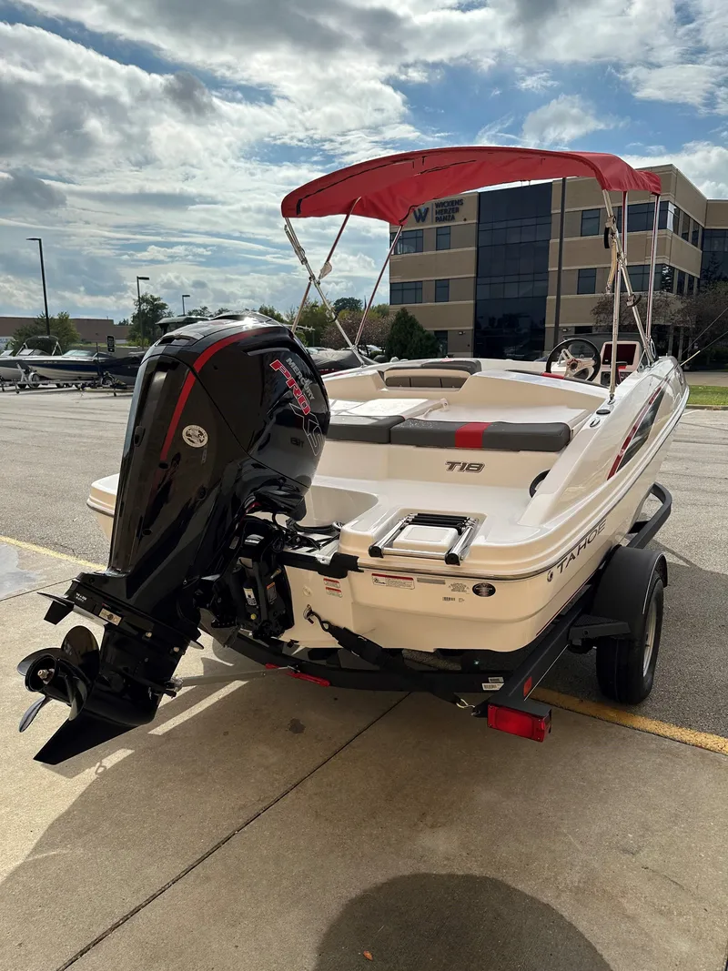 Slide: The Image of 2024 Tahoe T18 boat with red canopy and outboard motor in parking lot. - 2