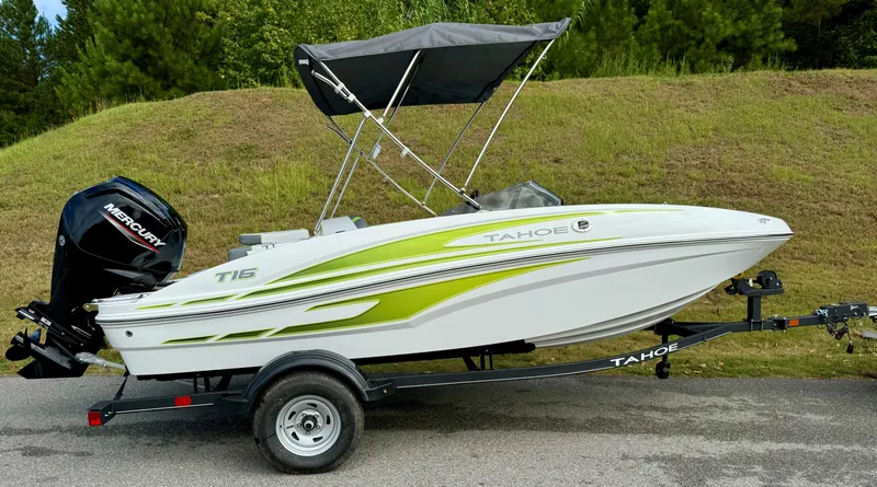 Slide: The Image of 2024 Tahoe T16 boat with green accents on a trailer, parked on a road. - 0