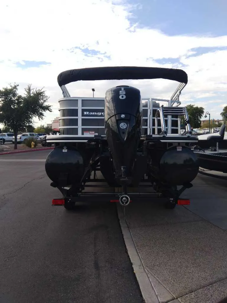 Slide: The Image of 2024 Ranger Reata 223C pontoon boat with outboard motor, parked on a street. - 3