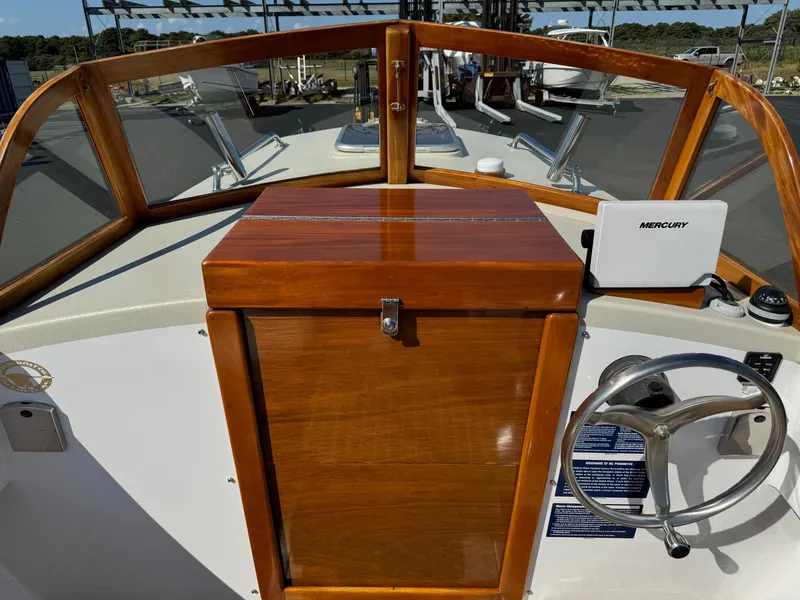 Slide: The Image of 2015 Devlin Pelicano 20 boat dashboard with wooden paneling and steering wheel. - 14