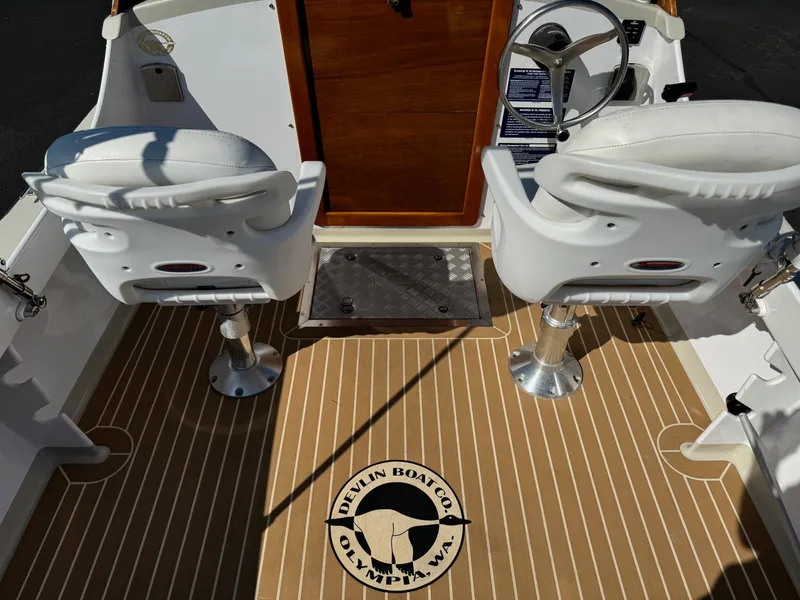 Slide: The Image of Interior of 2015 Devlin Pelicano 20 boat with two white seats and wooden flooring. - 16