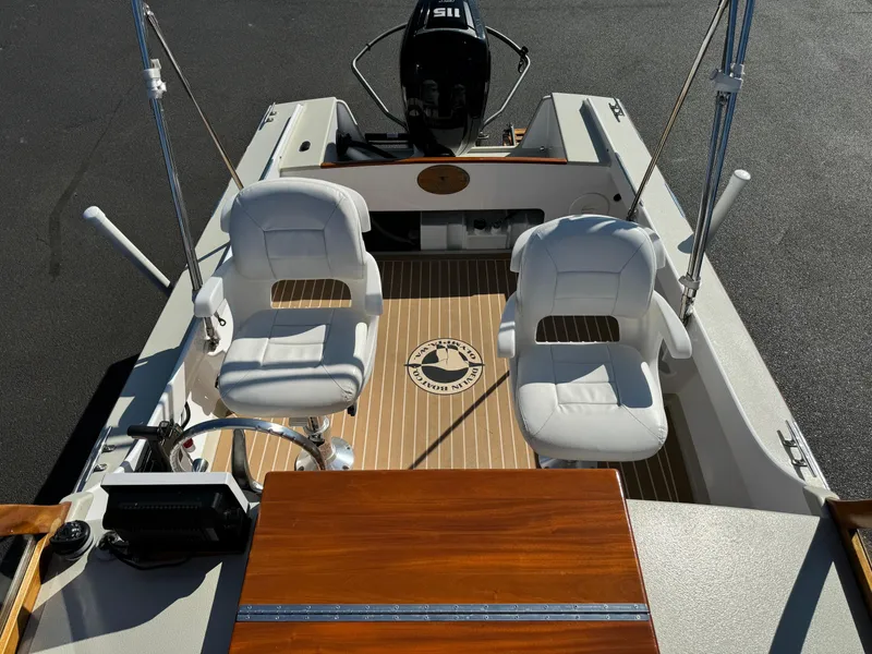 Slide: The Image of Devlin Pelicano 20 boat interior with two white seats, wooden accents, and steering console. - 18