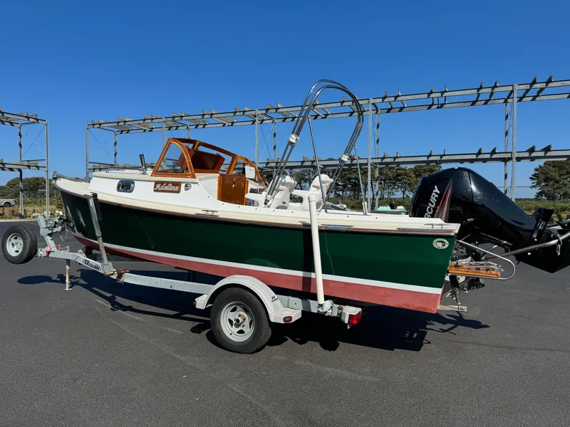 Slide: The Image of 2015 Devlin Pelicano 20 boat on trailer with outboard motor, parked outdoors. - 9