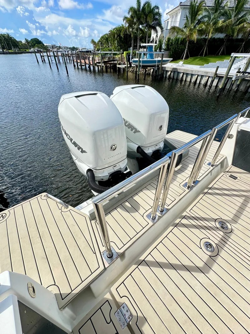 Slide: The Image of 2017 Axopar 37 Sun Top with twin outboard engines docked by a scenic waterfront. - 14