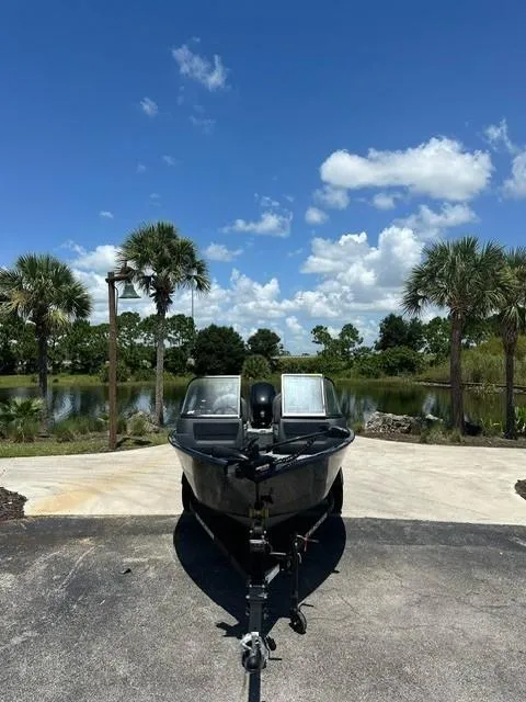 Slide: The Image of 2025 Bass Tracker PGV16WT boat on trailer, parked near scenic lake with palm trees. - 3