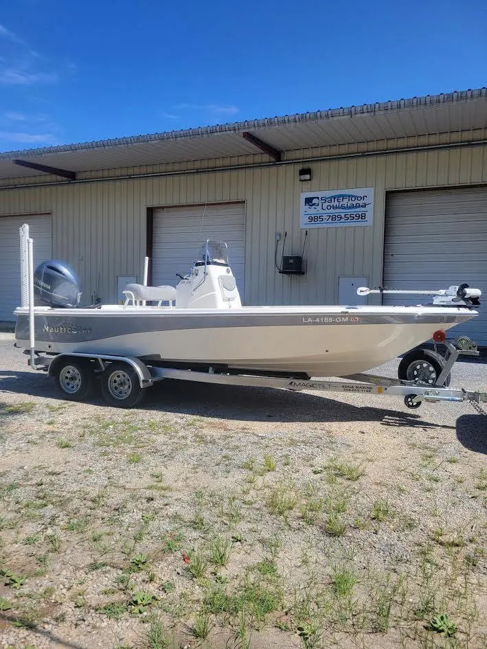 Slide: The Image of 2021 NauticStar 215 XTS boat on trailer, parked outside a warehouse. - 1