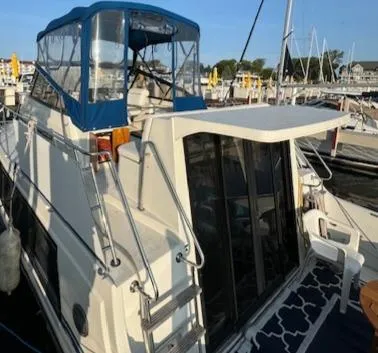 Slide: The Image of 1989 Carver 32 Mariner yacht docked at marina, featuring blue canopy and spacious deck area. - 14