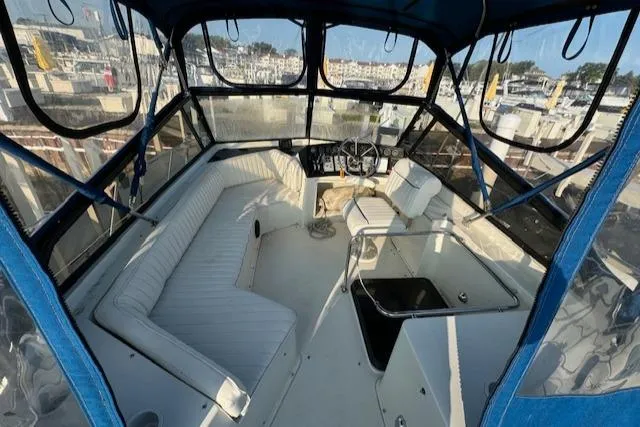 Slide: The Image of 1989 Carver 32 Mariner boat interior with seating and helm, docked at marina. - 15