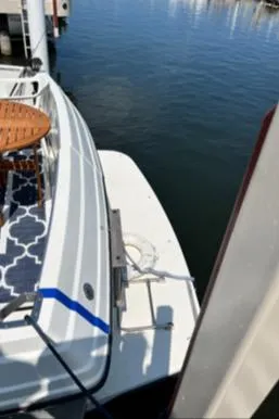 Slide: The Image of 1989 Carver 32 Mariner docked, featuring a stylish deck with a patterned rug and wooden table. - 6