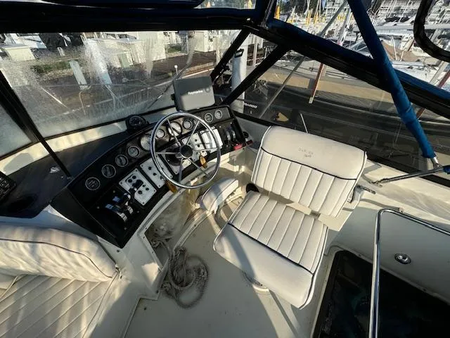 Slide: The Image of 1989 Carver 32 Mariner helm with steering wheel, control panel, and cushioned seating. - 8