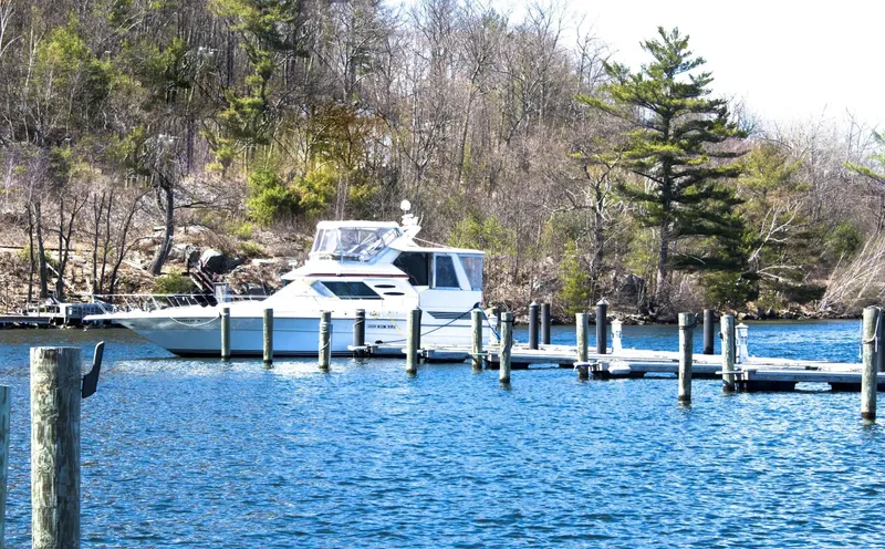 Slide: The Image of 1989 Sea Ray 440 Aft Cabin yacht docked on a serene lake with wooded shoreline. - 14