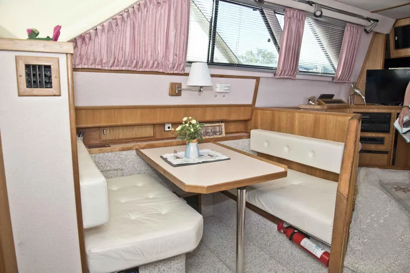 Slide: The Image of 1989 Sea Ray 440 Aft Cabin interior with dining area, wood accents, and pink curtains. - 21