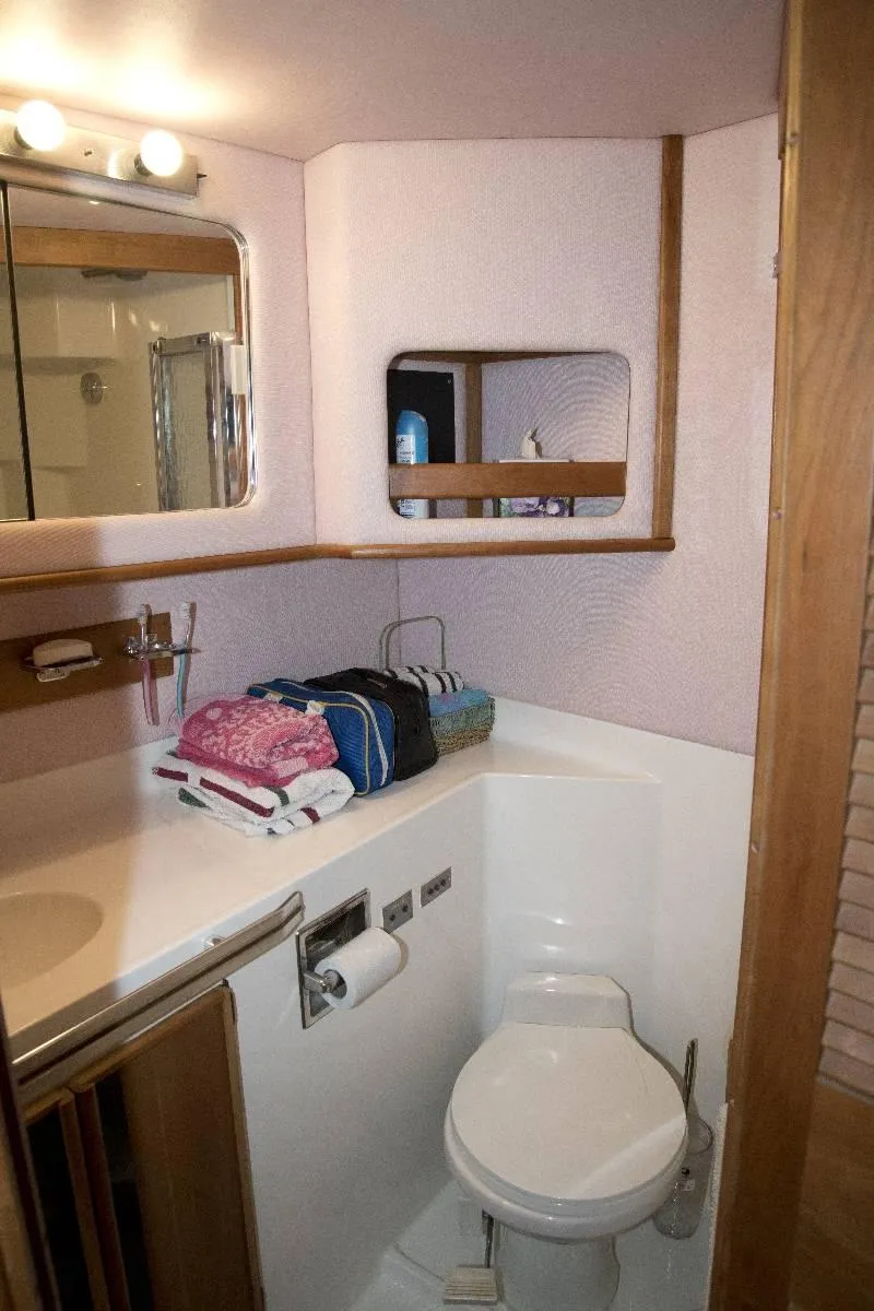 Slide: The Image of 1989 Sea Ray 440 Aft Cabin bathroom with toilet, sink, and mirror. - 24