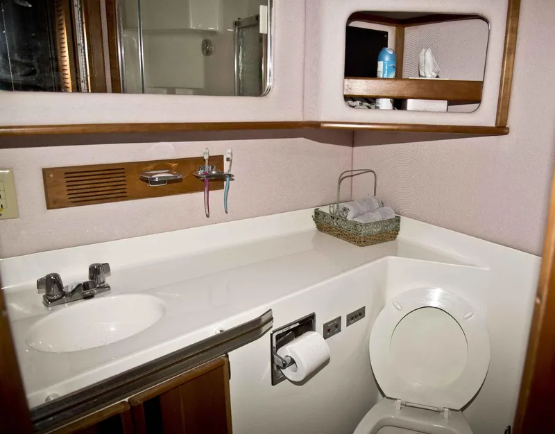 Slide: The Image of 1989 Sea Ray 440 Aft Cabin bathroom with sink, toilet, and storage shelves. - 26
