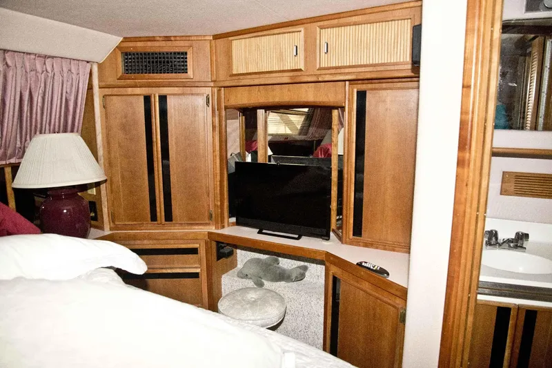Slide: The Image of 1989 Sea Ray 440 Aft Cabin interior with wood cabinetry, TV, and lamp. - 27