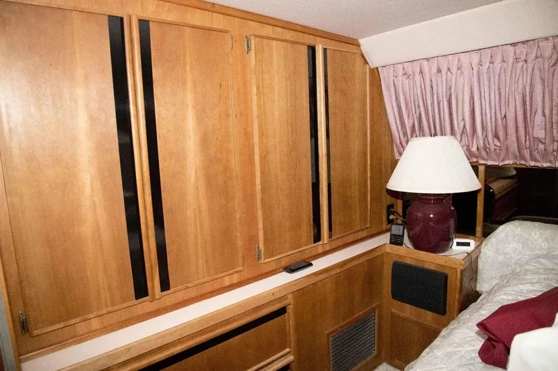 Slide: The Image of Interior of 1989 Sea Ray 440 Aft Cabin with wood cabinets and lamp. - 28