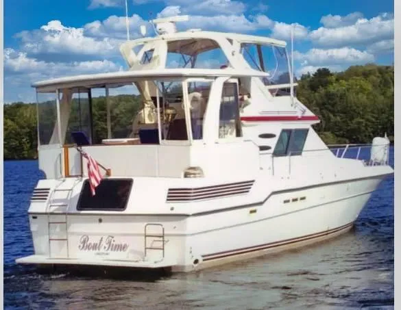 Slide: The Image of 1989 Sea Ray 440 Aft Cabin yacht on a serene lake with blue skies. - 6