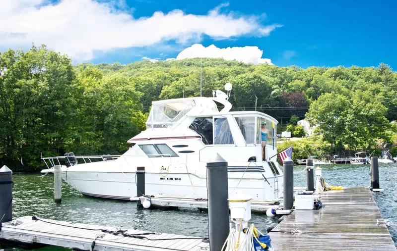 Slide: The Image of 1989 Sea Ray 440 Aft Cabin yacht docked by lush green trees. - 7