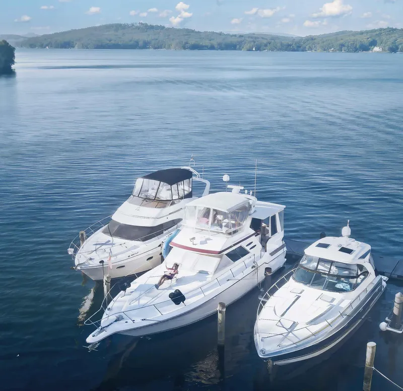 Slide: The Image of Three yachts docked on a serene lake, featuring a 1989 Sea Ray 440 Aft Cabin. - 8