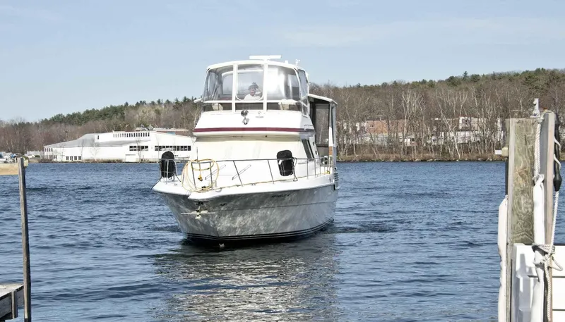 Slide: The Image of 1989 Sea Ray 440 Aft Cabin yacht on a calm river near a dock. - 9