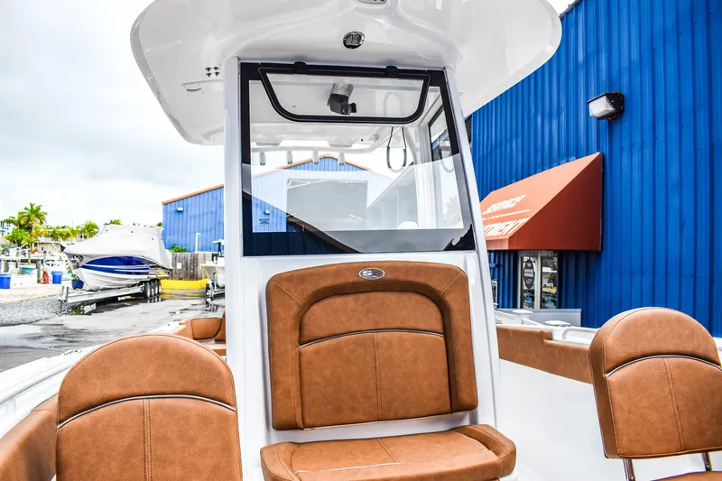 Slide: The Image of 2025 Sea Hunt Ultra 255 SE boat with brown seating, docked near blue building. - 12