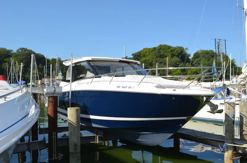 The Image of 2023 Regal 36 Grande Coupe boat docked in a marina under clear blue skies. - 0