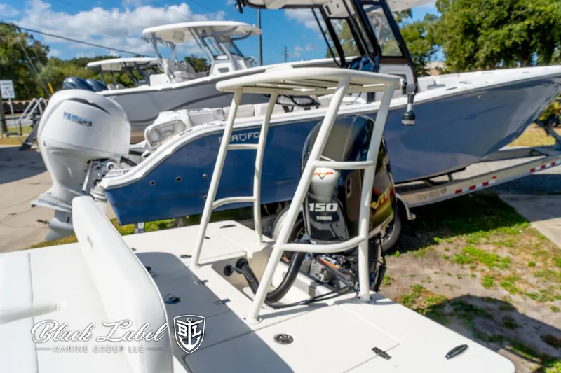 Slide: The Image of 2025 Hewes 18 Redfisher boat with Yamaha 150 engine, parked outdoors. - 18