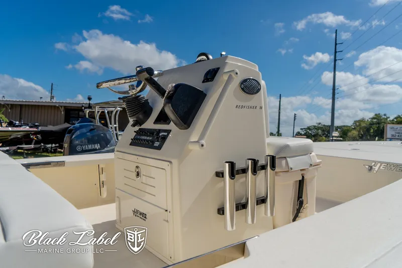 Slide: The Image of 2025 Hewes 18 Redfisher boat console with steering wheel and controls under a clear blue sky. - 4