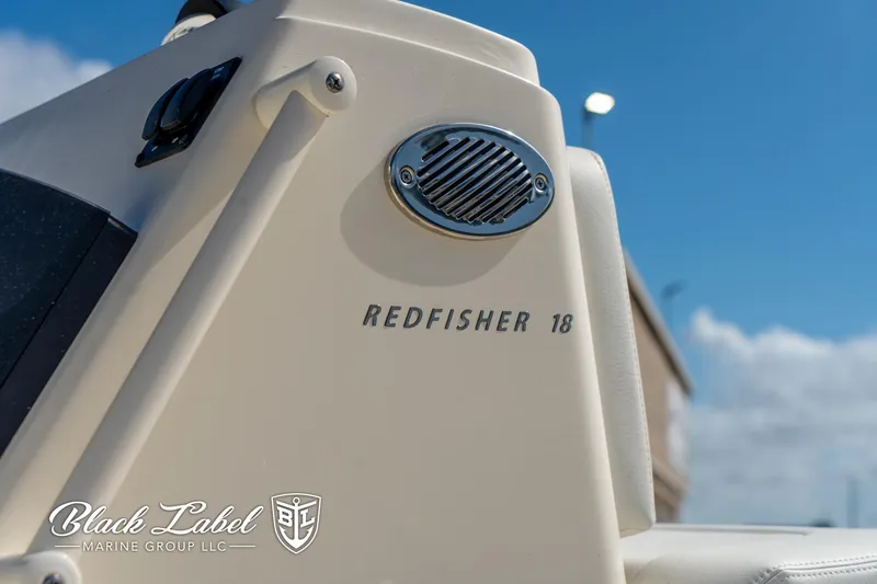 Slide: The Image of 2025 Hewes 18 Redfisher boat detail with logo, against a clear blue sky. - 5