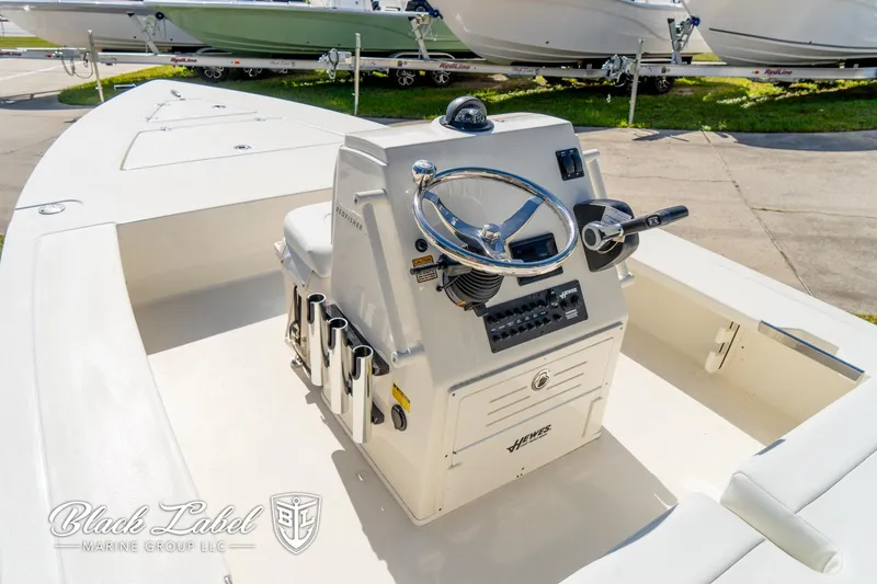 Slide: The Image of 2025 Hewes 18 Redfisher boat console with steering wheel and controls, docked outdoors. - 8