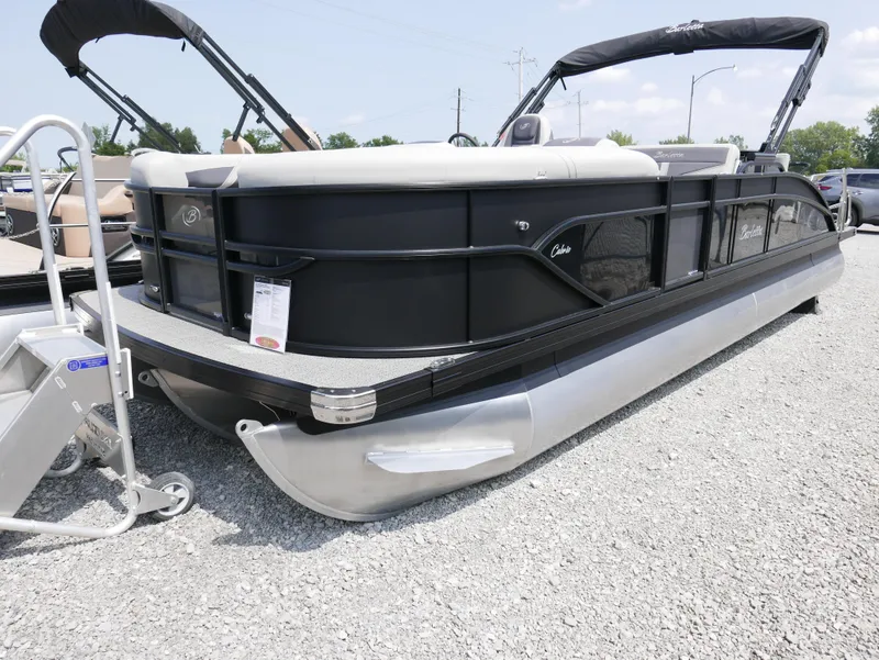 Slide: The Image of 2025 Barletta Cabrio 24UE pontoon boat displayed on gravel lot. - 2