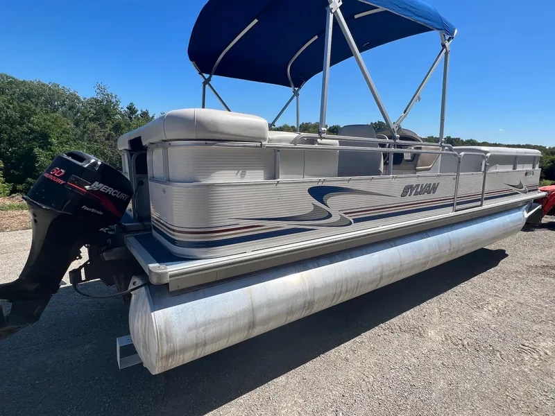 Slide: The Image of 2003 Sylvan Mirage pontoon boat with blue canopy and Mercury outboard motor. - 14