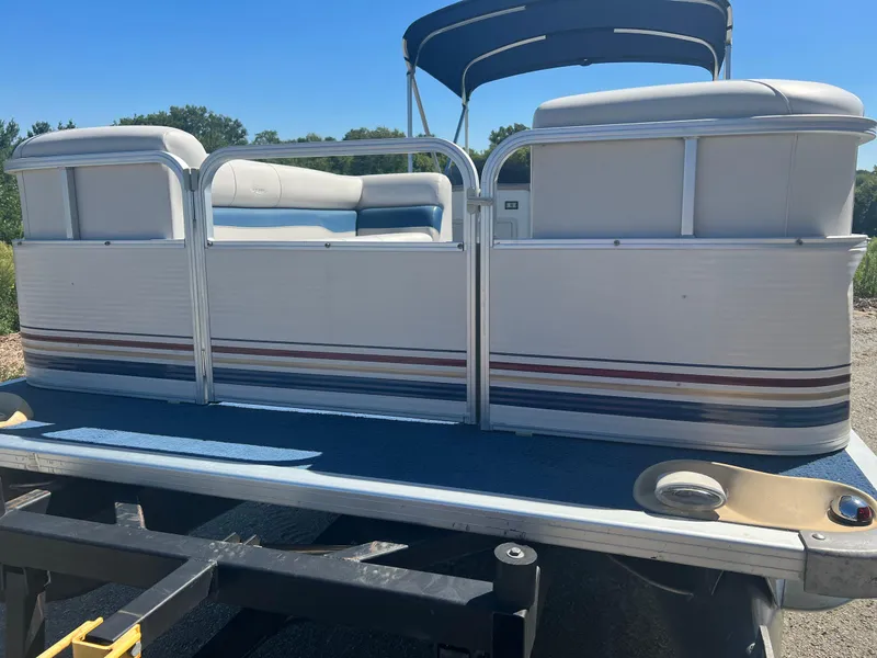 Slide: The Image of 2003 Sylvan Mirage pontoon boat on trailer, featuring white and blue seating. - 8