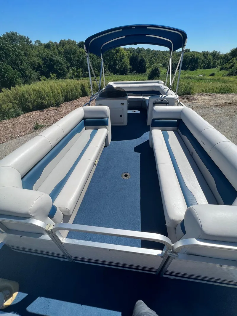 Slide: The Image of 2003 Sylvan Mirage pontoon boat with spacious seating and canopy, set against a natural backdrop. - 9