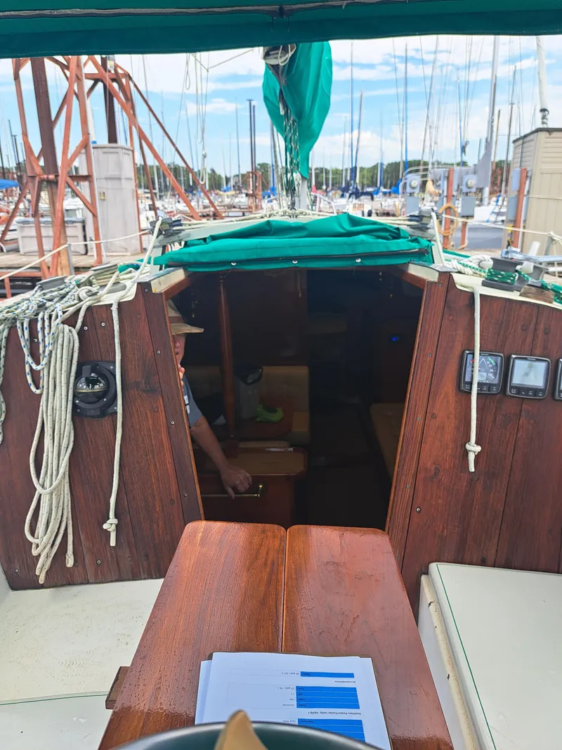Slide: The Image of 1979 Newport Mark II sailboat cockpit with green canopy and marina background. - 12
