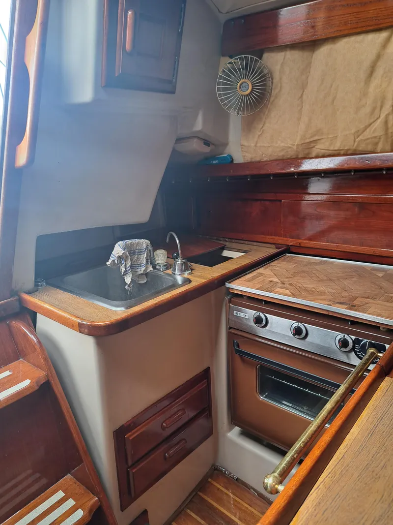 Slide: The Image of 1979 Newport Mark II boat kitchen with wooden cabinets and stove. - 23