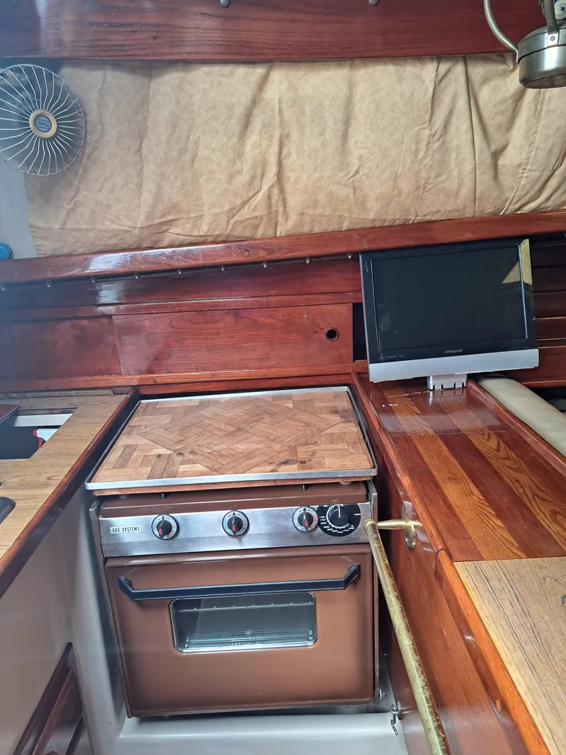 Slide: The Image of 1979 Newport Mark II yacht interior with wooden cabinetry and stove. - 24