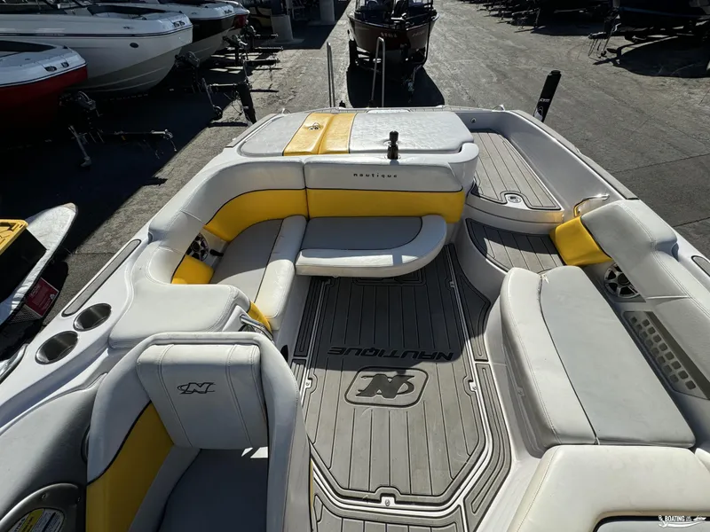 Slide: The Image of 2007 Nautique SV211 boat interior with yellow and gray seating, docked among other boats. - 6