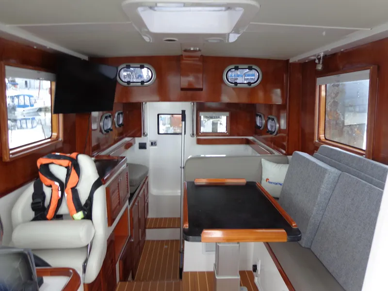 Slide: The Image of Interior of 2020 SeaPiper Pilothouse boat with wood finish and seating area. - 13
