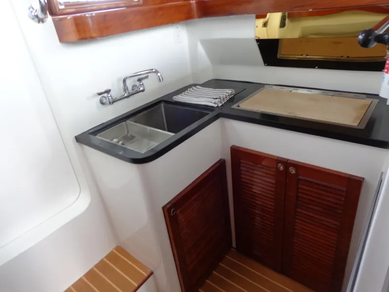 Slide: The Image of 2020 SeaPiper Pilothouse kitchen with sink, countertop, and wooden cabinets. - 19
