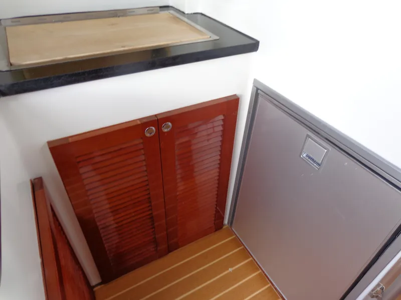 Slide: The Image of 2020 SeaPiper Pilothouse interior with wooden cabinets and compact fridge. - 22