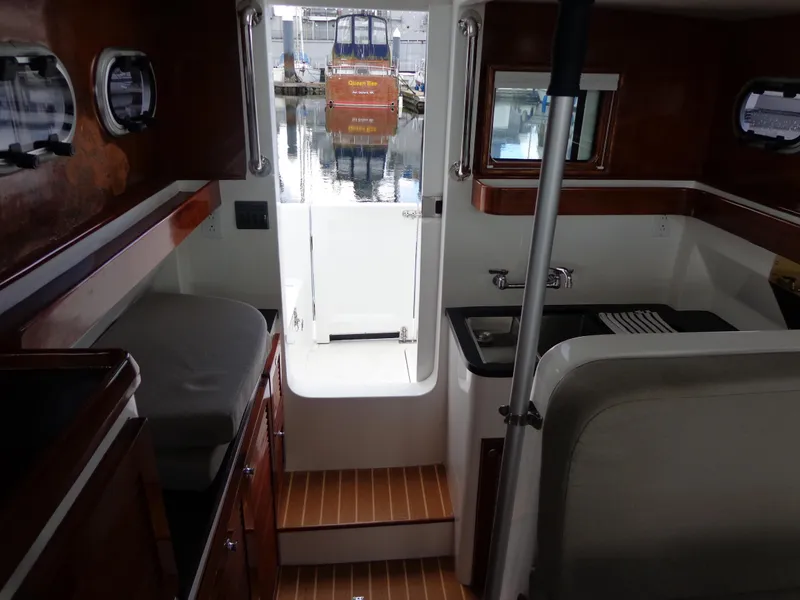 Slide: The Image of Interior of 2020 SeaPiper Pilothouse boat with wood accents and compact kitchen area. - 24