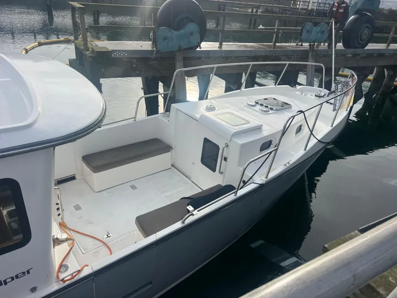 Slide: The Image of 2020 SeaPiper Pilothouse boat docked at a marina, featuring a spacious deck and seating area. - 3