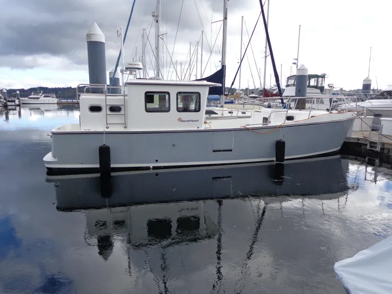 Slide: The Image of 2020 SeaPiper Pilothouse boat docked in a marina, reflecting on calm water. - 6