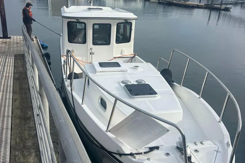 Slide: The Image of 2020 SeaPiper Pilothouse boat docked at marina with person securing it. - 8